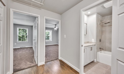 a hallway with open doors and a bathroom